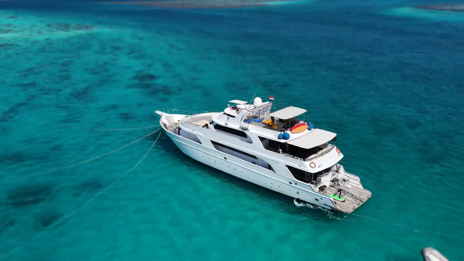 The Vessel, a 35 m wooden liveaboard at anchor over clear Red Sea water, seen from the air off the stern quarter