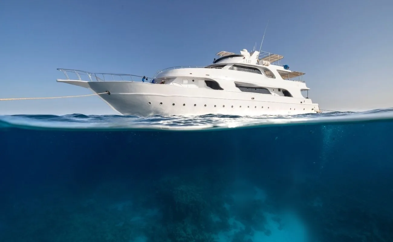 The liveaboard at anchor in the Red Sea, seen from the waterline, the sea surface splitting the frame